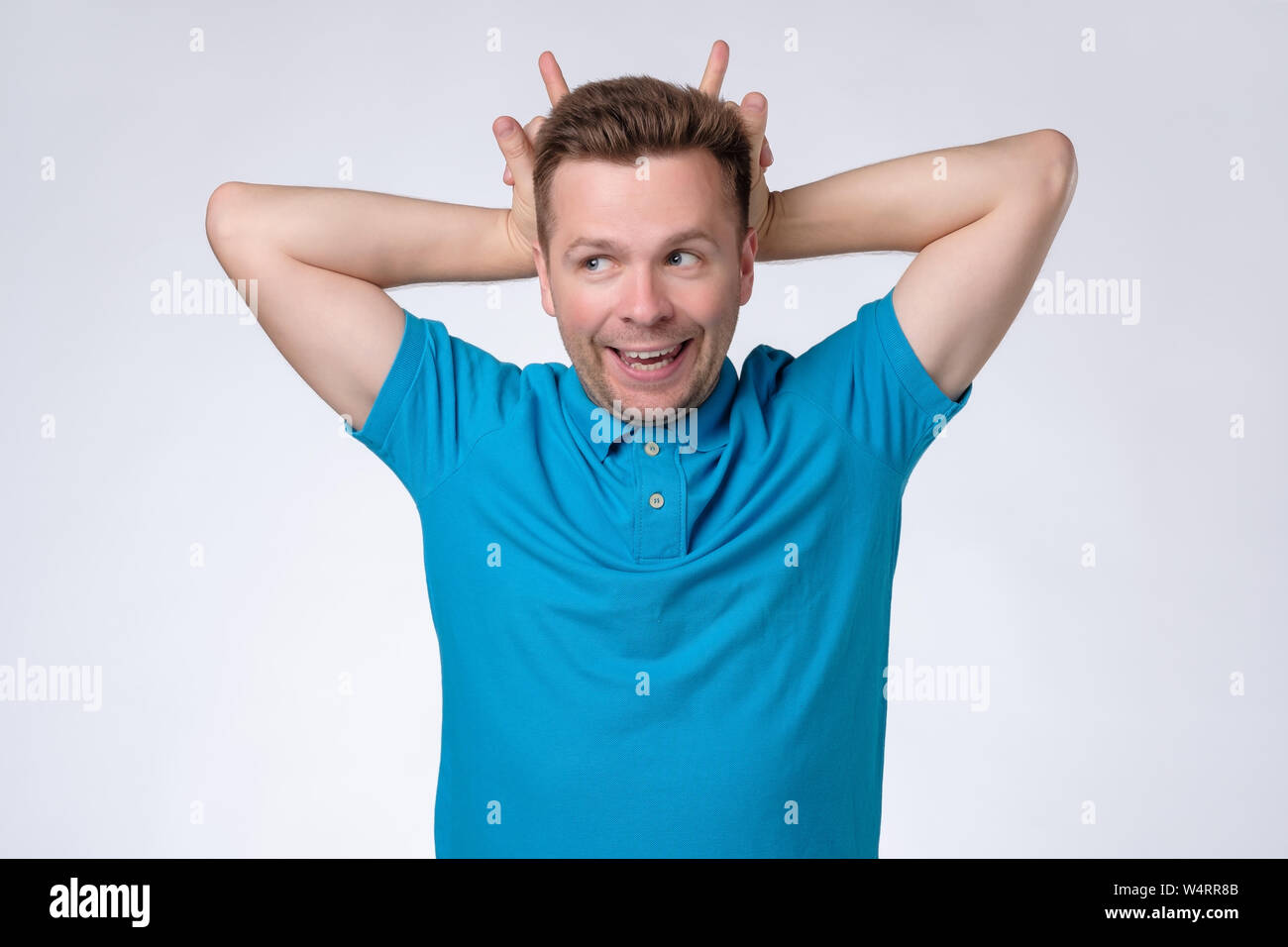 Mann mit Hörnern Geste auf dem Kopf und Kamera Stockfoto