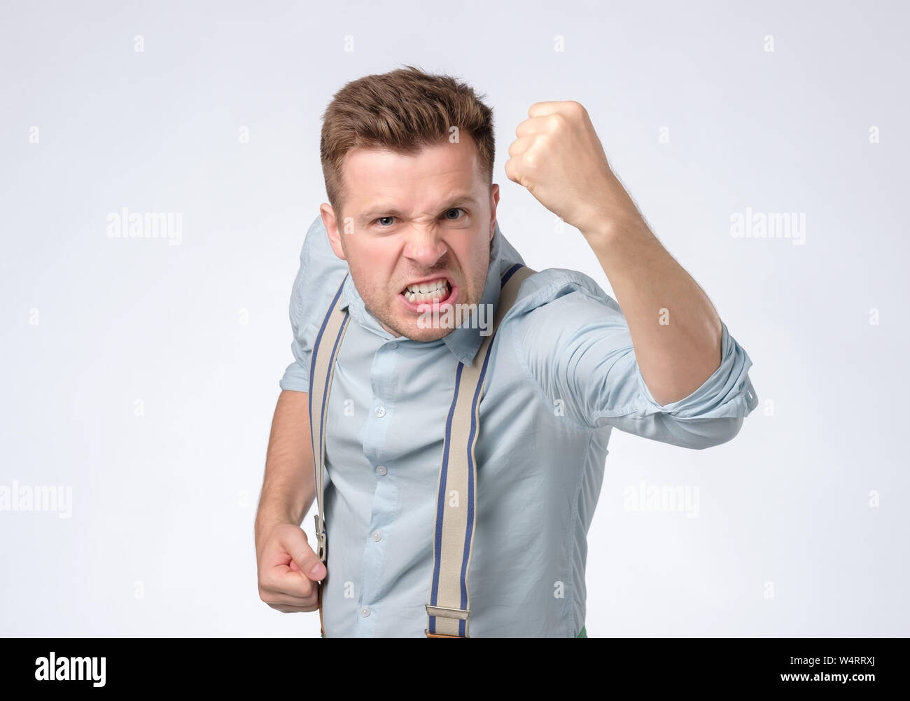 Zorniger junger Mann stehend und droht mit Faust Stockfoto