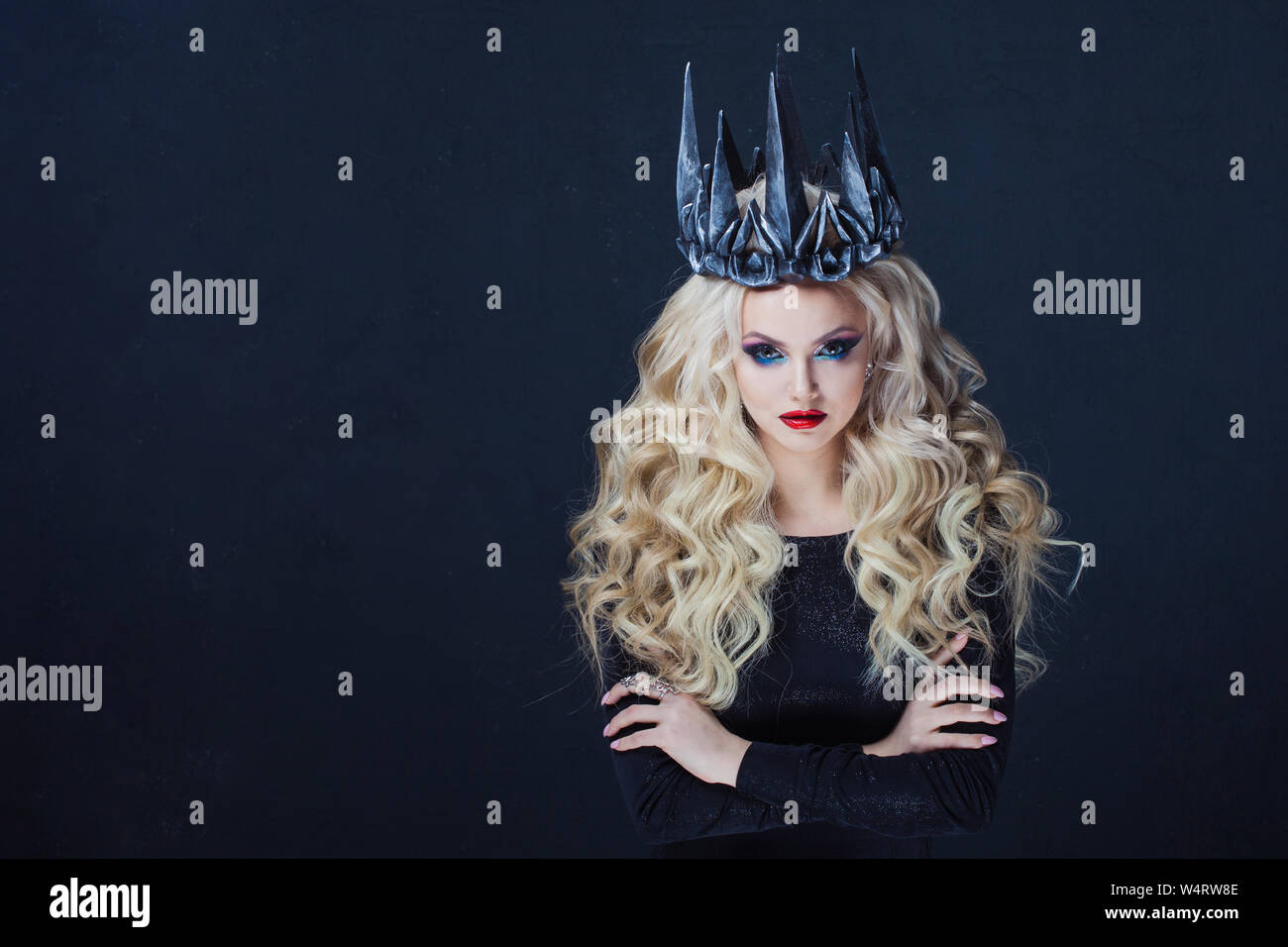 Porträt einer gotischen Königin. Schöne junge blonde Frau in Metall Krone und schwarzen Mantel. Mystisches Bild Stockfoto