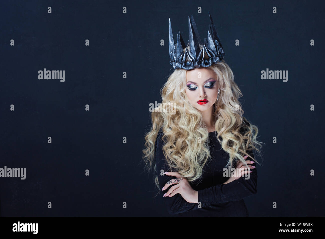 Porträt einer gotischen Königin. Schöne junge blonde Frau in Metall Krone und schwarzen Mantel. Mystisches Bild Stockfoto