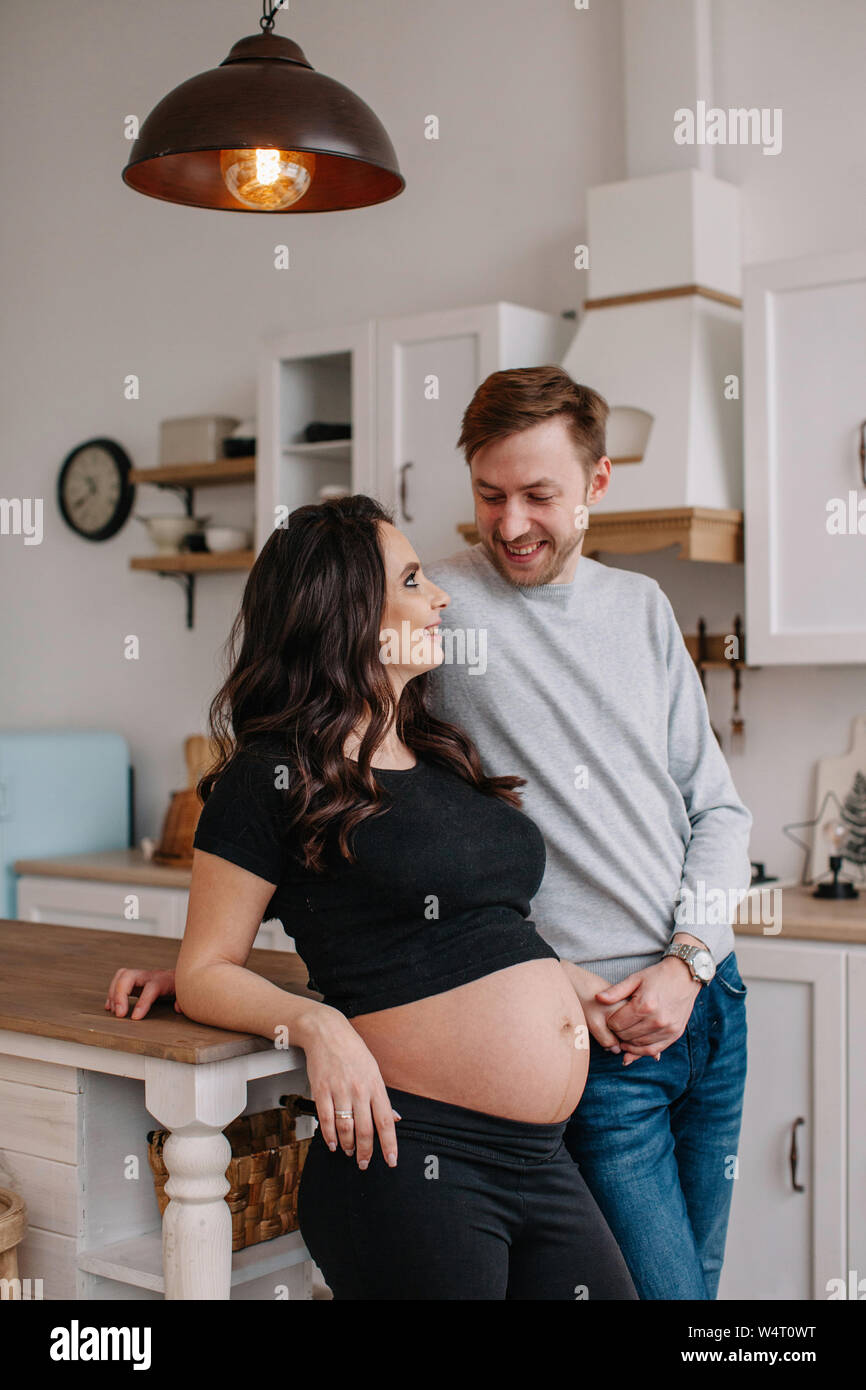 Schwangere Frau steht in der Küche mit ihrem Ehemann Stockfoto
