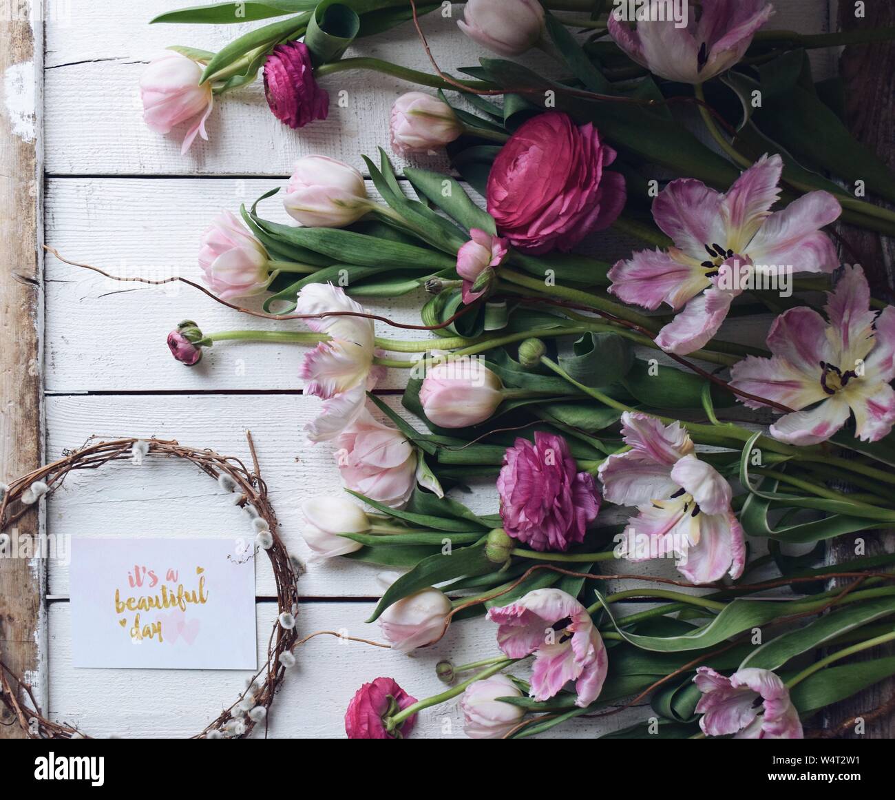 Rosa Tulpen und Ranunkeln mit einer Karte sagen, dass es ein schöner Tag Stockfoto