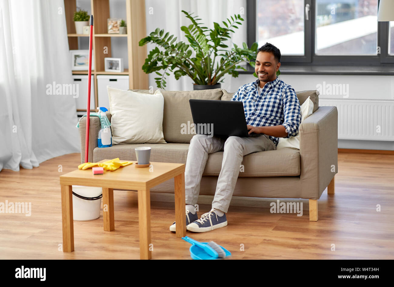 Mann mit Laptop nach Hause Reinigung Stockfoto