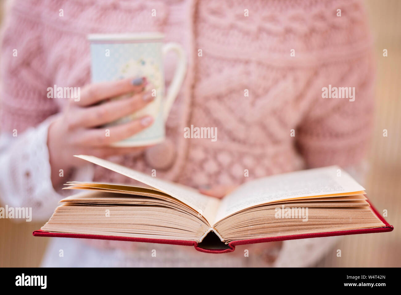 Junges Mädchen mit einem Buch und einer Tasse Kaffee Stockfoto