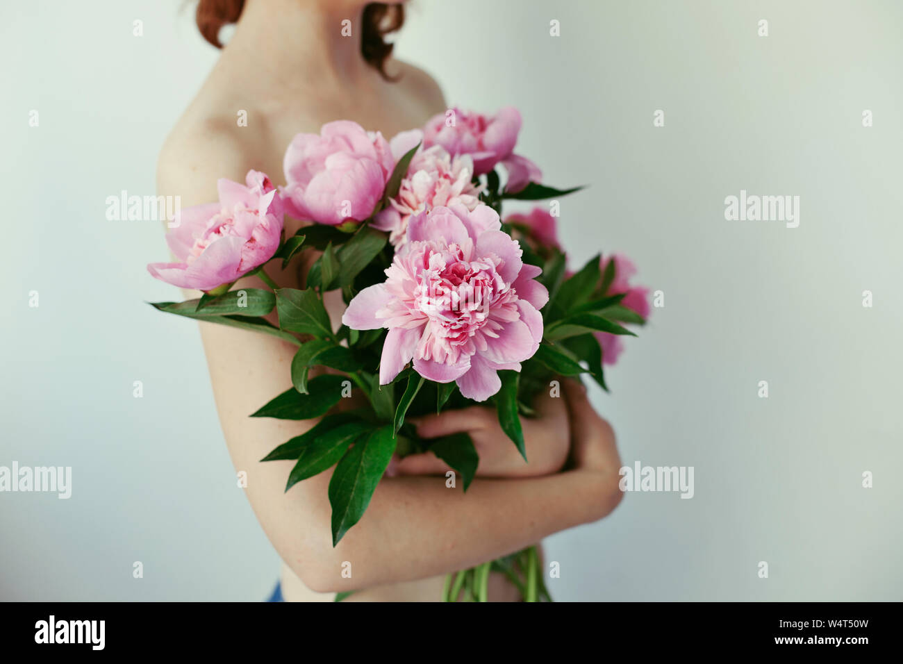 Nahaufnahme einer jungen Frau mit einem Blumenstrauß von Pfingstrosen Stockfoto