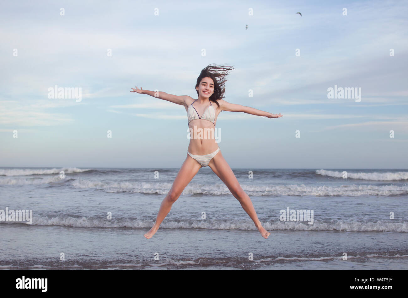 Lächelnd Jugendmädchen in der Luft am Strand jumping, Argentinien Stockfoto