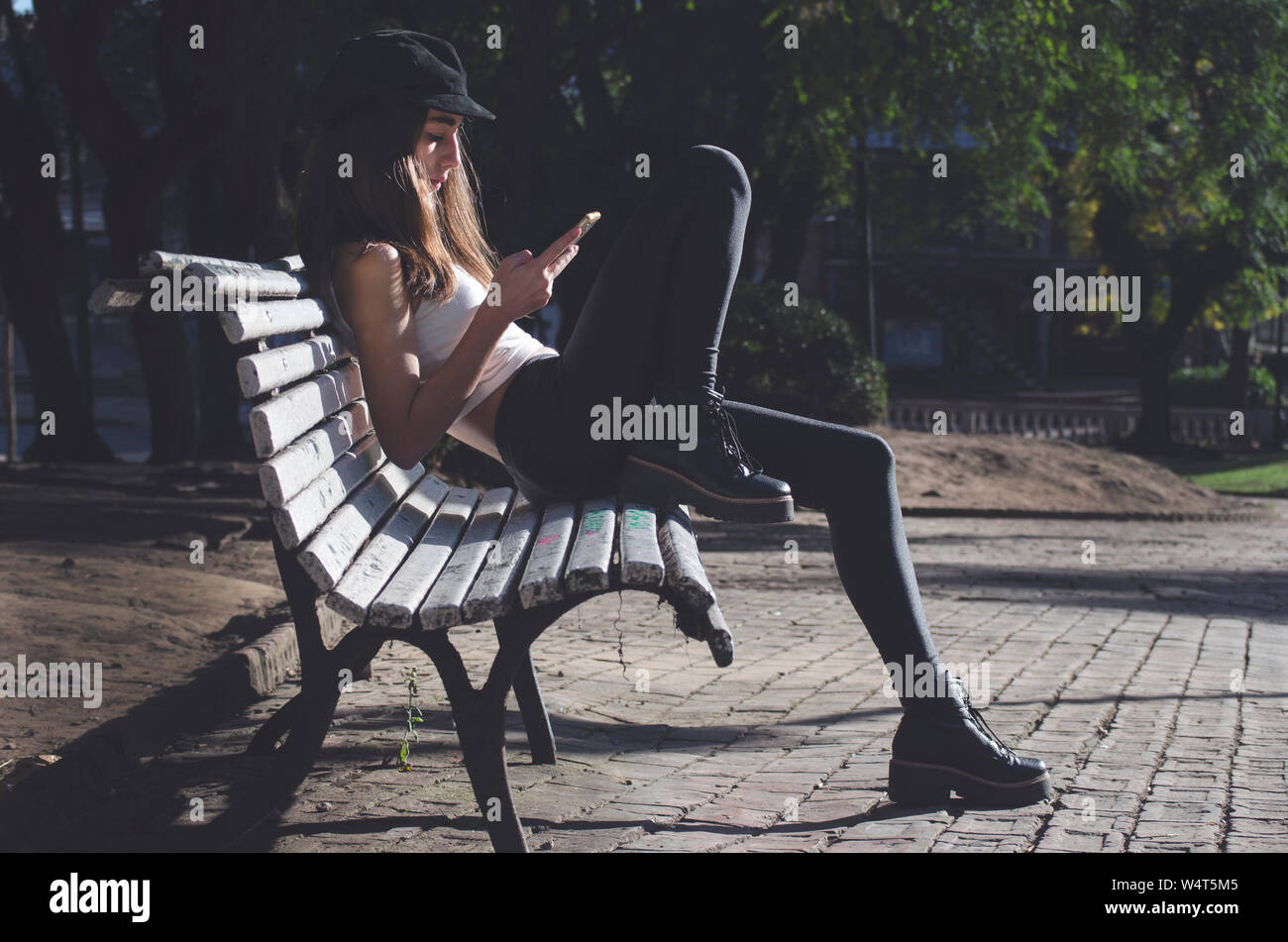 Junges Mädchen sitzen auf einer Bank an Ihrem Mobiltelefon suchen, Argentinien Stockfoto