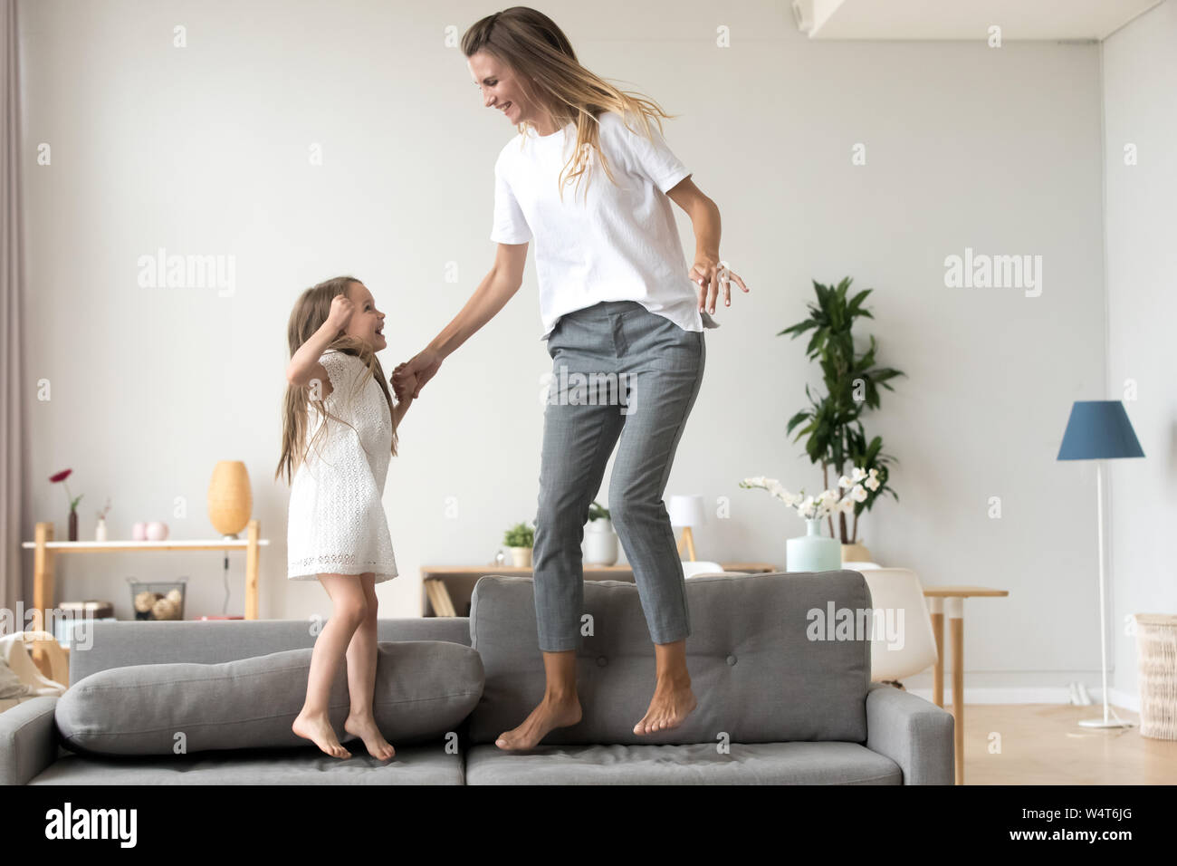 Fröhliche Mutter und Tochter springen auf der Couch zu Hause Stockfoto
