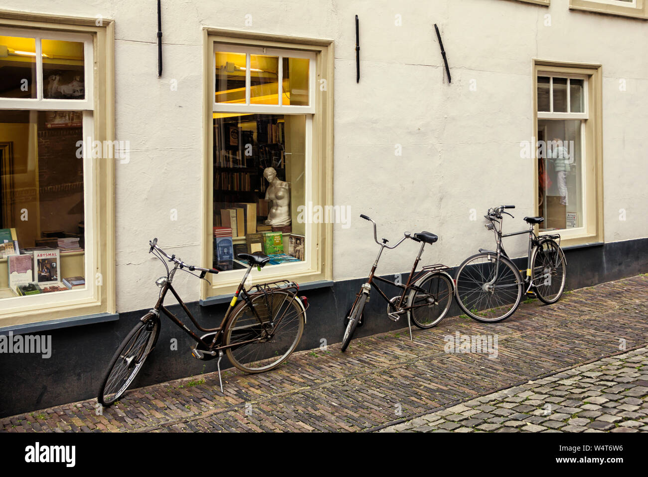 Leiden, Holland, Niederlande, 17. April 2019. Üblichen Straße und Book Shop windows Ansicht mit einer Kopie der Venus Statue, traditionelle Häuser und abgestellte Fahrräder Stockfoto