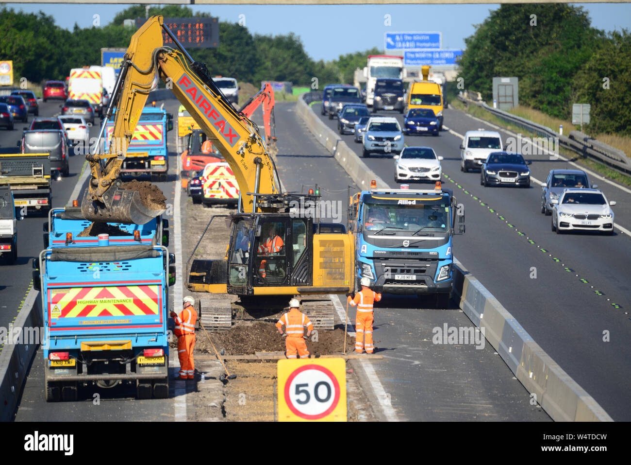 Digger in zentrale Reservierung laden Lkw's mit Schutt upgrade Bauarbeiten an der Autobahn M62 Leeds Yorkshire Großbritannien arbeiten Stockfoto