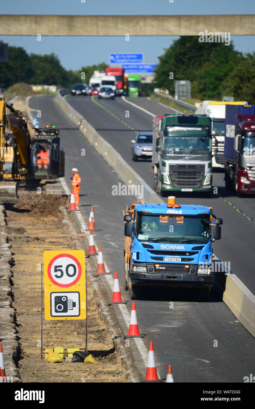 Digger in zentrale Reservierung laden Lkw's mit Schutt upgrade Bauarbeiten an der Autobahn M62 Leeds Yorkshire Großbritannien arbeiten Stockfoto