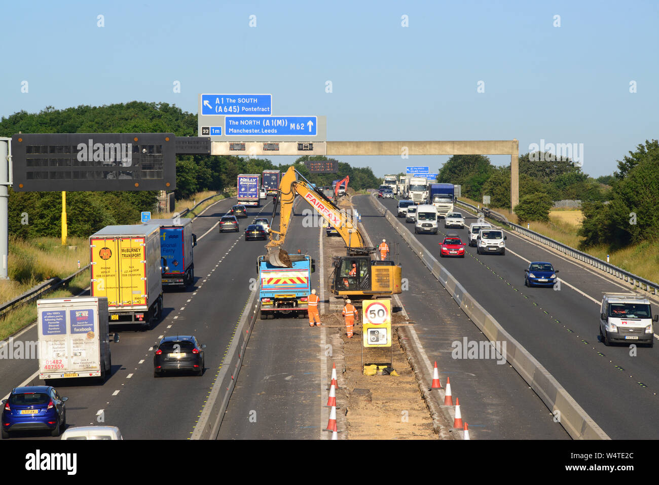 Digger in zentrale Reservierung laden Lkw's mit Schutt upgrade Bauarbeiten an der Autobahn M62 Leeds Yorkshire Großbritannien arbeiten Stockfoto