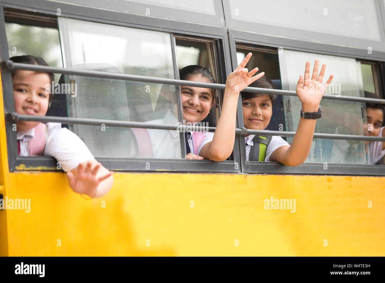 Glückliche Kinder Hand winken aus dem Fenster der Schule Bus Stockfoto