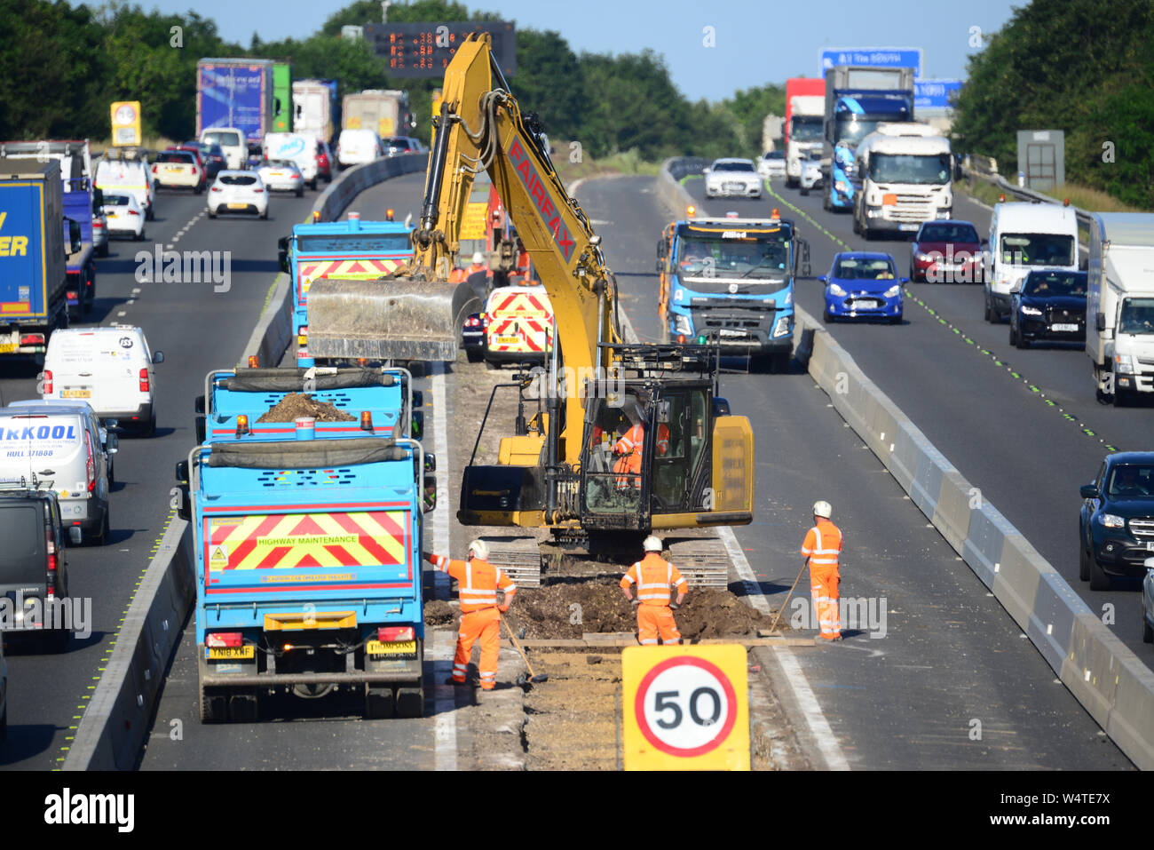 Digger in zentrale Reservierung laden Lkw's mit Schutt upgrade Bauarbeiten an der Autobahn M62 Leeds Yorkshire Großbritannien arbeiten Stockfoto