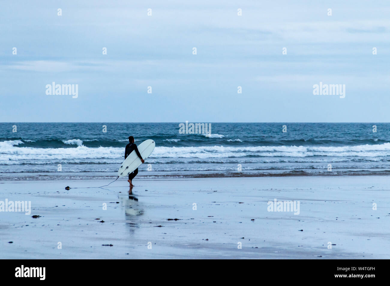 Eine einzelne männliche Surfer Köpfe für das Meer bei Dämmerung, Westward Ho!, Devon, Großbritannien Stockfoto