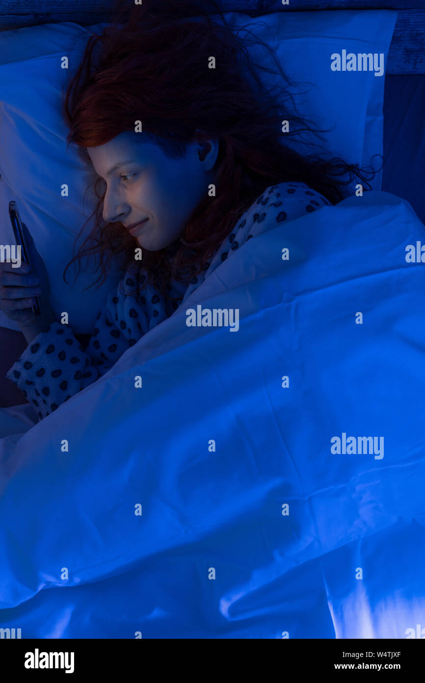 Junge Frauen sind mit dem Smart Phone auf dem Bett/in Liebe Stockfoto