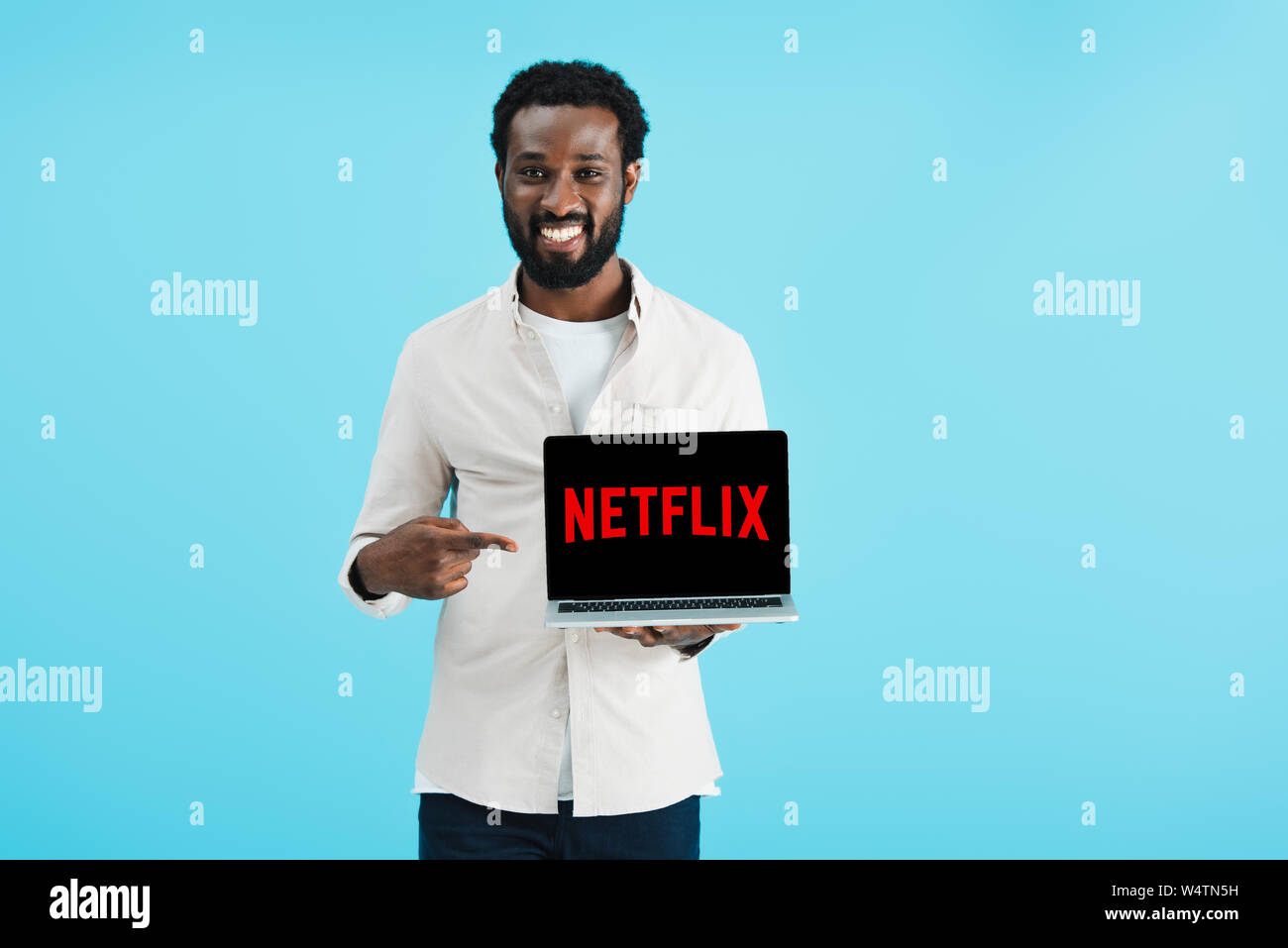 Kiew, Ukraine - Mai 17, 2019: Lächelnde afrikanische amerikanische Mann am Laptop mit Netflix Website verweisen, auf Blau isoliert Stockfoto