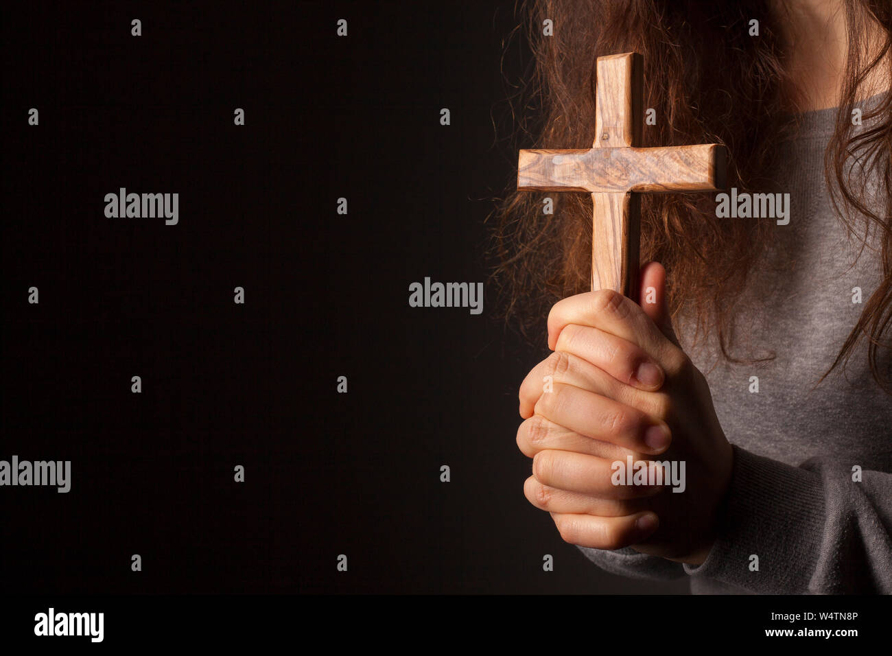 Hände mit Kreuz auf dunklem Hintergrund Stockfoto