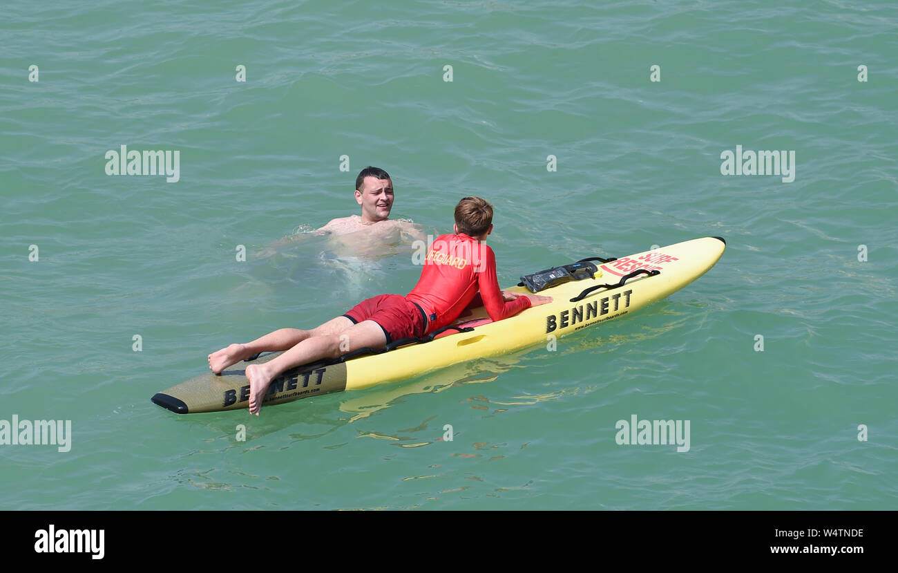 Brighton UK 25. Juli 2019 - ein Rettungsschwimmer hat ein Wort mit einem Schwimmer, der von der nahe gelegenen Pier ins Meer auf einem anderen heißen, sonnigen Tag in Großbritannien gesprungen war, wie Meteorologen prognostizieren Rekordtemperaturen für Teile des Südostens. Foto: Simon Dack/Alamy leben Nachrichten Stockfoto