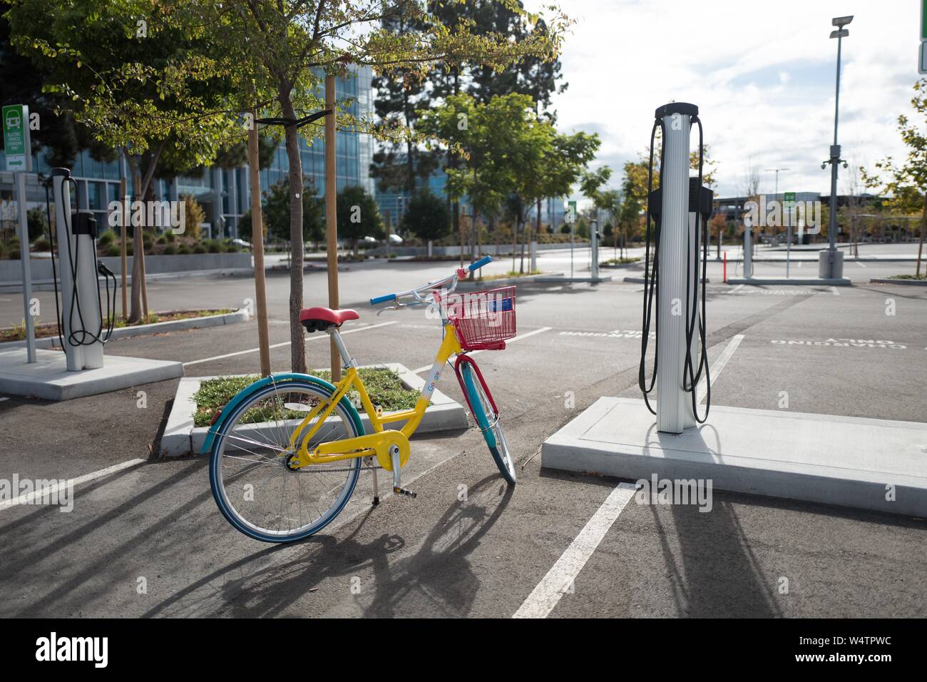 Eine bunte Google Fahrrad ist neben elektrischen Fahrzeug geparkt Ladestationen an der Firma Moffett Ort Büro im Silicon Valley Stadt Sunnyvale, Kalifornien, 28. Oktober 2018. () Stockfoto