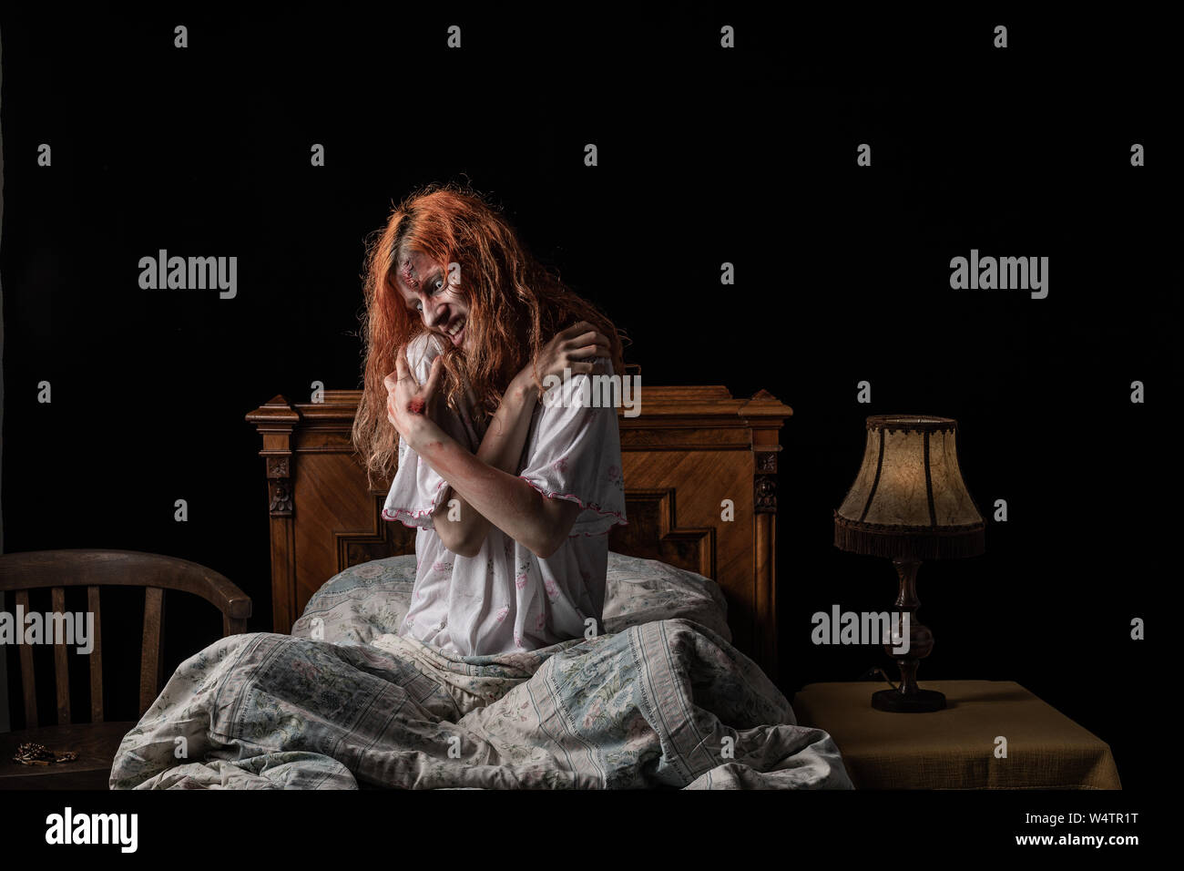 Furchtsame Frau besessen von Teufel im Bett. Exorzismus der Priester. Stockfoto