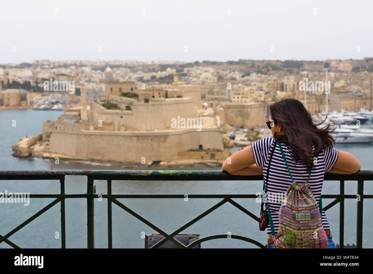 Weibliche Touristen mit dunklen Haaren auf Fort St. Angelo in der Ferne. Stockfoto