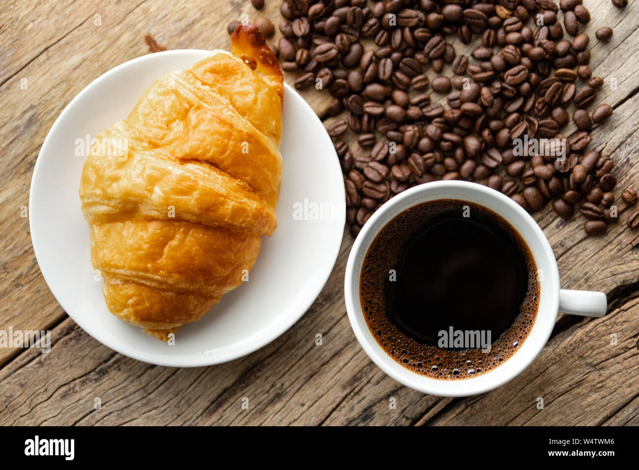 Kontinentales Frühstück mit frischen Croissants und heißen Kaffee auf hölzernen Hintergrund, Deko mit Kaffeebohnen Stockfoto