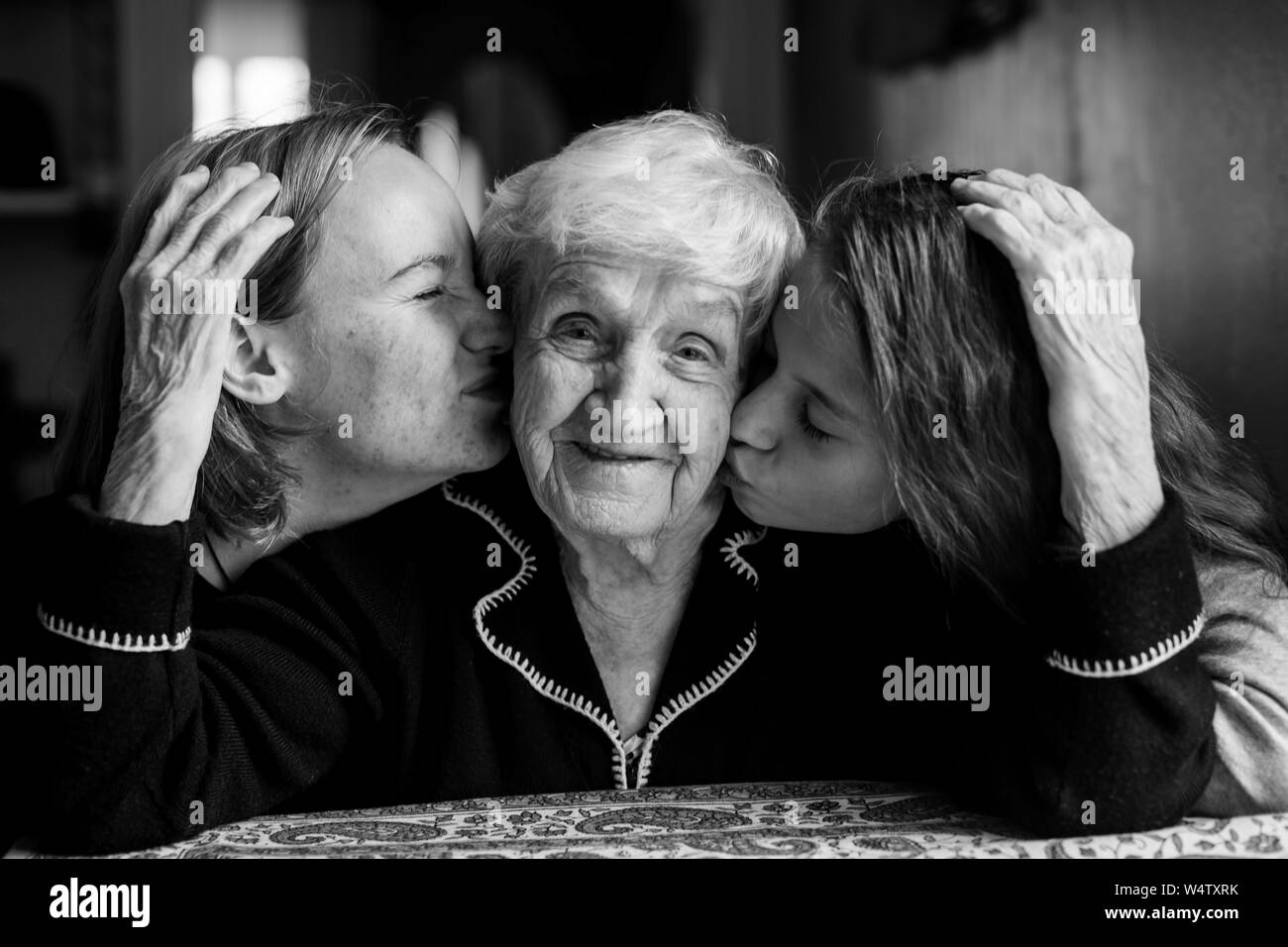 Eine alte Frau posiert für ein Portrait mit zwei Enkelinnen. Schwarz-weiß Foto. Stockfoto