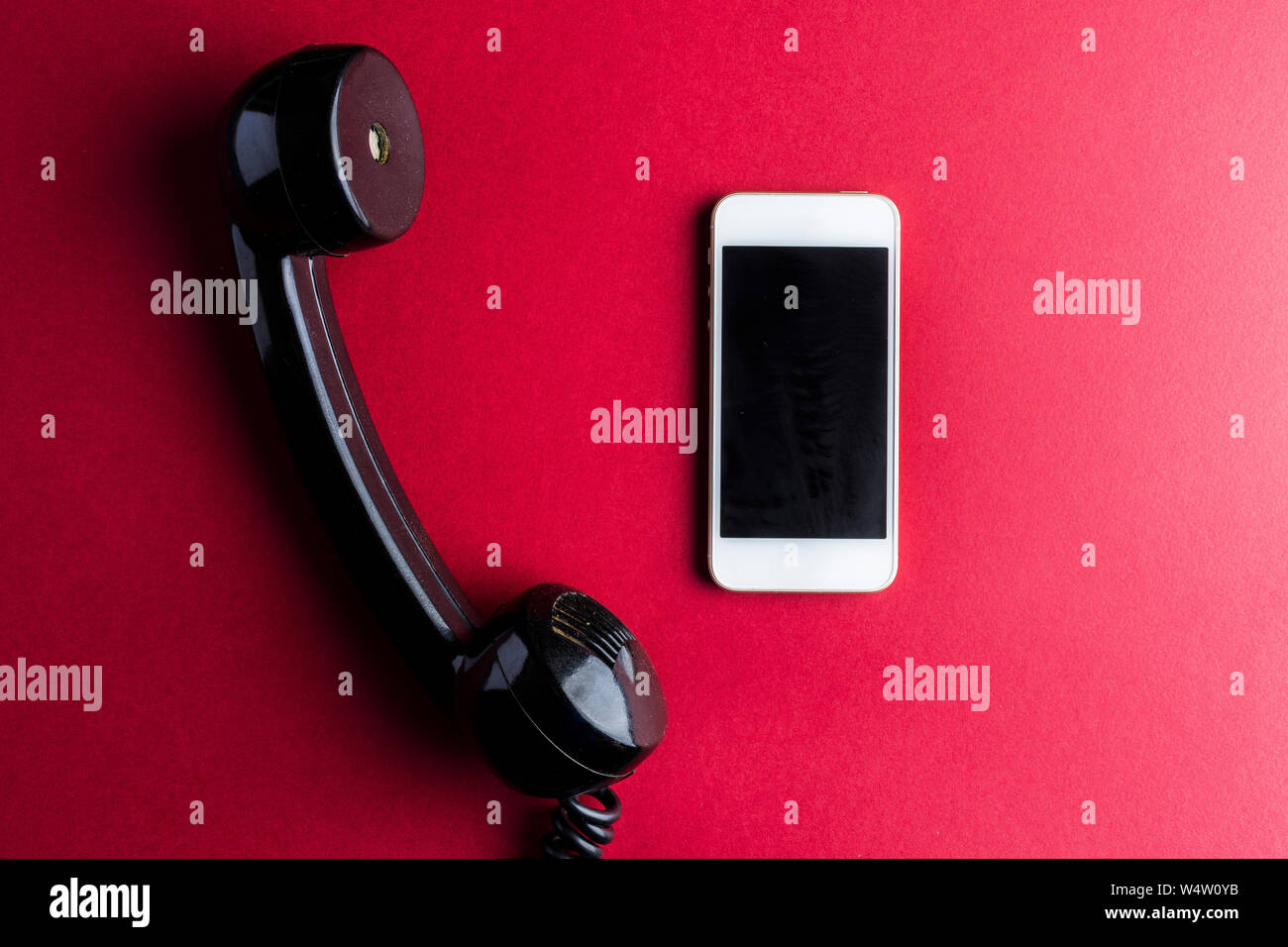 Vintage Telefonhörer vs Smartphone auf Rot Stockfoto