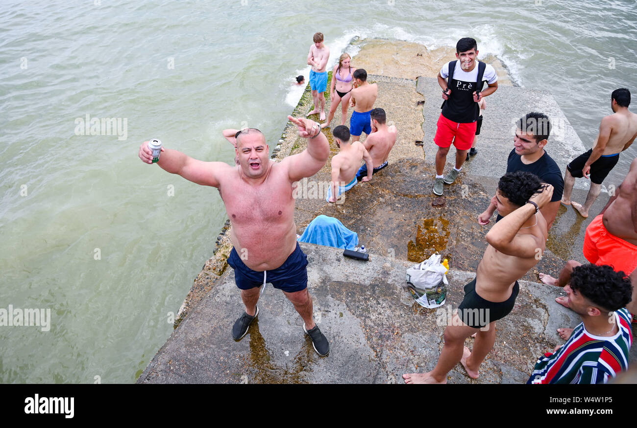 Brighton UK 25. Juli 2019 - Junge Männer tauchen Sie ein in das Meer von einem groyne am Brighton Beach als Besucher einen anderen heißen, sonnigen Tag in Großbritannien genießen mit meteorologen Vorhersagen Rekordtemperaturen für Teile des Südostens. Foto: Simon Dack/Alamy leben Nachrichten Stockfoto