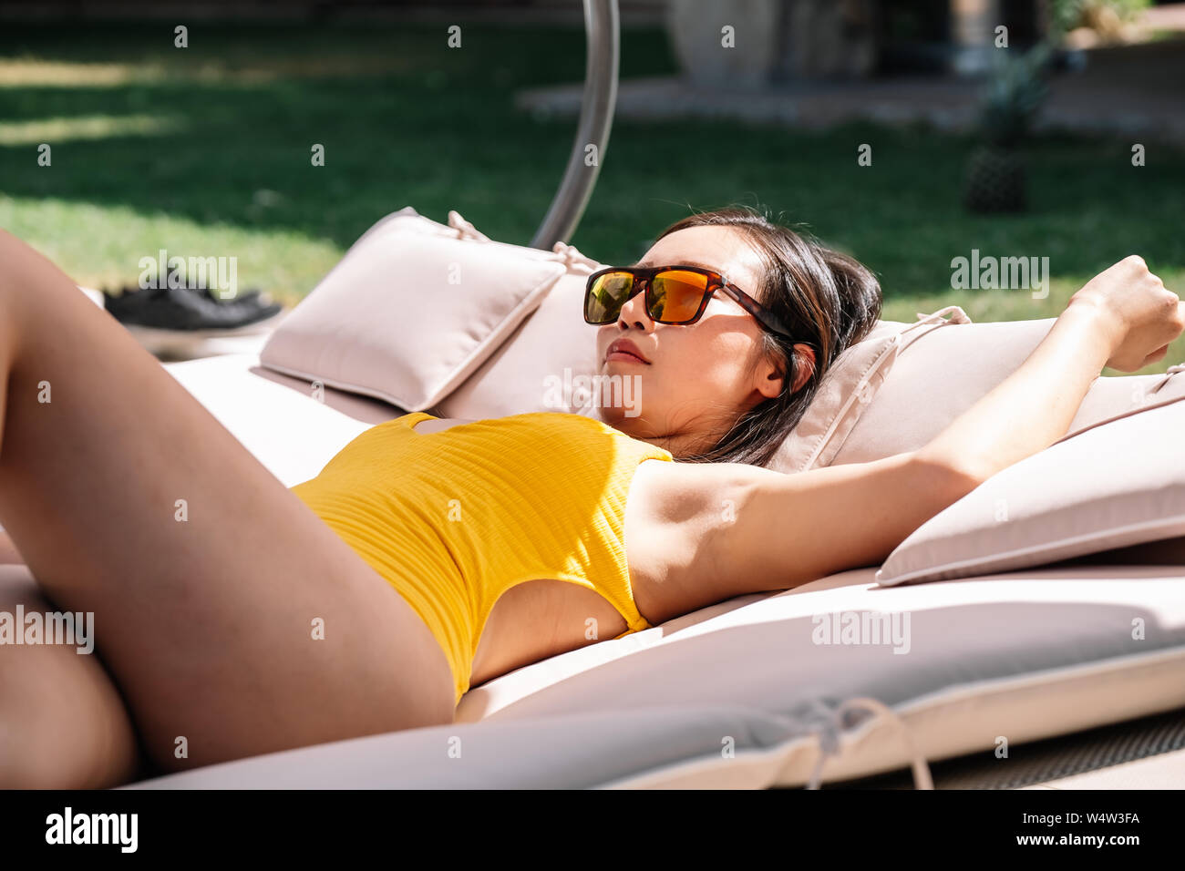 Chinesische Frau mit Sonnenbrille liegen auf einer Liege Stockfoto