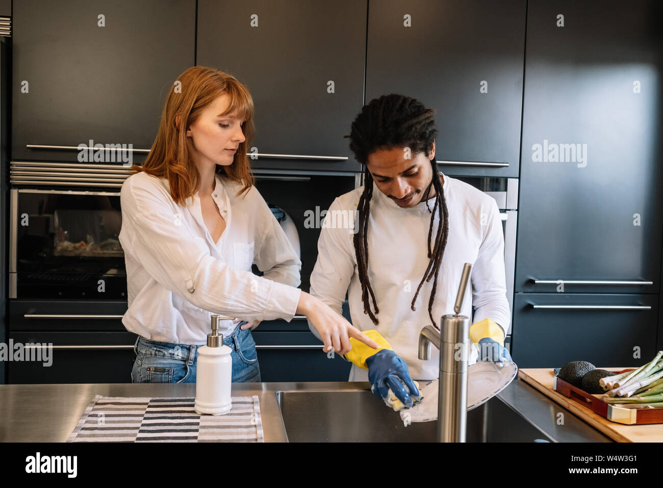 Weiße Frau bestellen afro-amerikanischen Jungen zu sauberes Geschirr Stockfoto