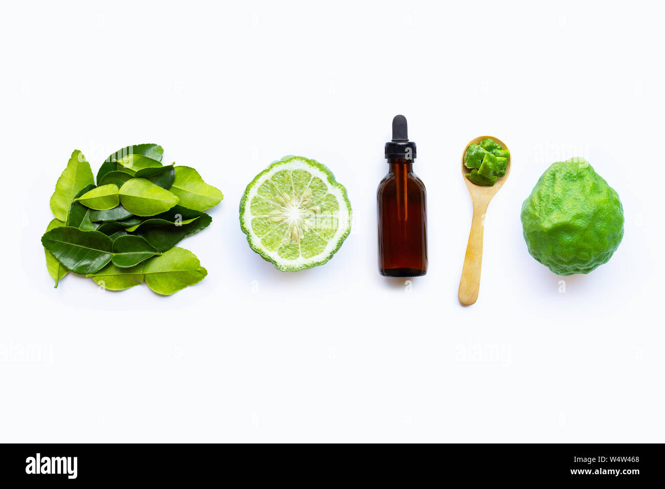 Flasche ätherische Öl und frische Kaffernlimette oder Bergamotte Obst mit Blättern auf weißem Hintergrund. Stockfoto