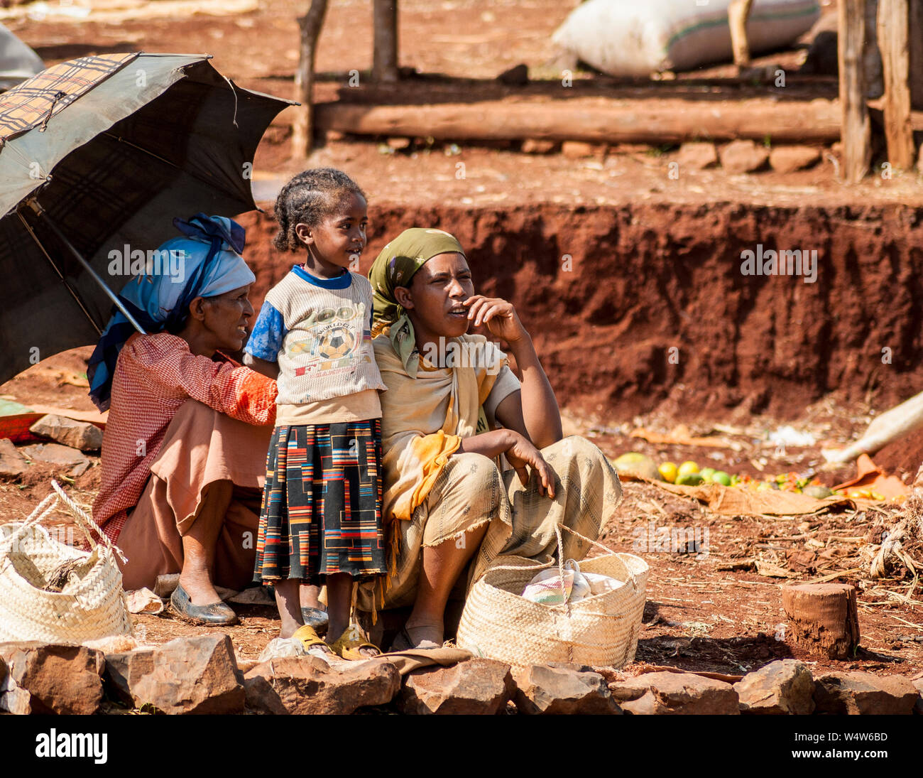 Zwei junge Frauen und ein Kind auf der Suche nach ihrer Produktion in einer ländlichen Markt in Illubabor, Äthiopien Stockfoto