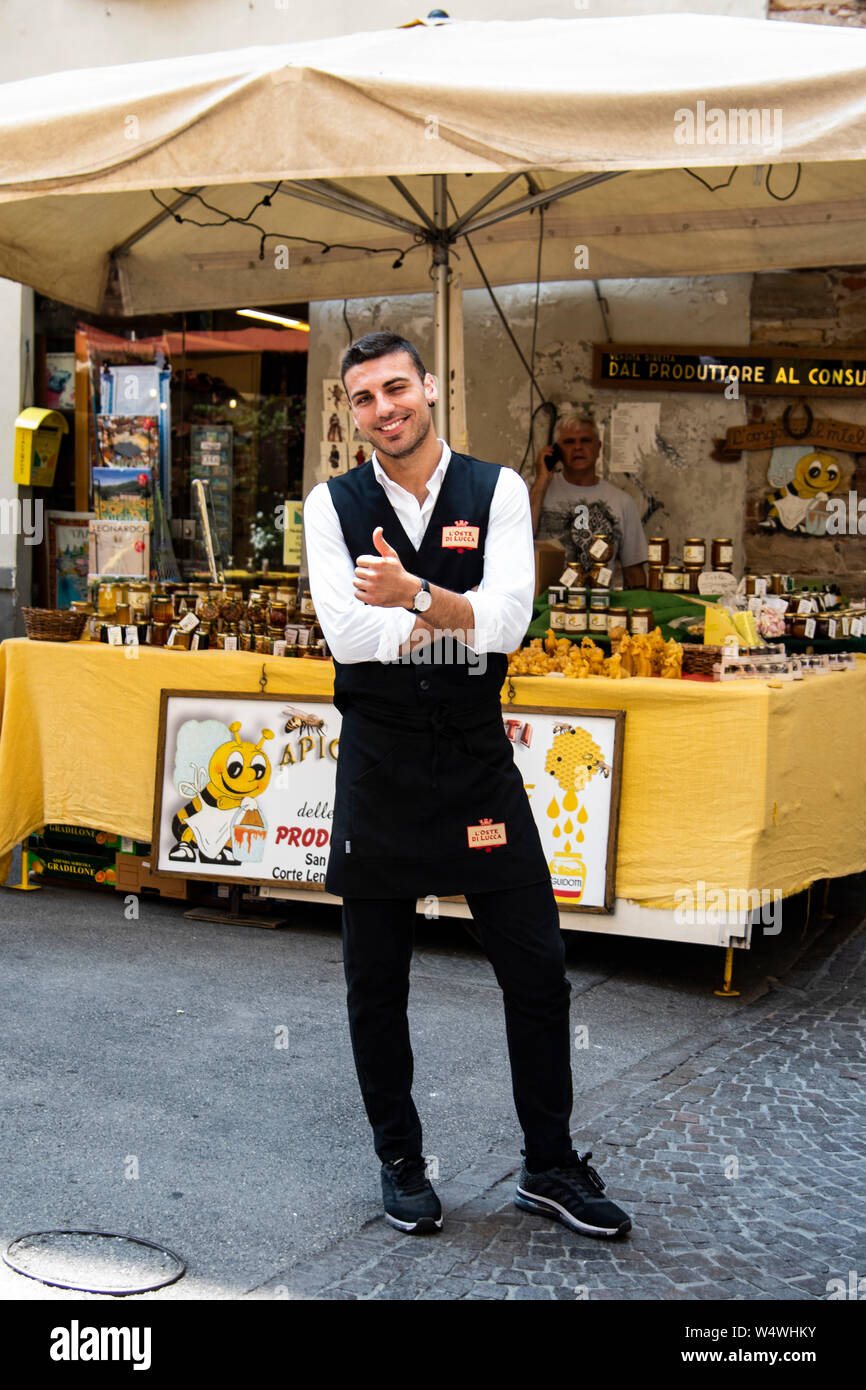 Stattliche männliche Kellner winks und gibt Daumen bis zu der Kamera in Lucca, Italien Stockfoto