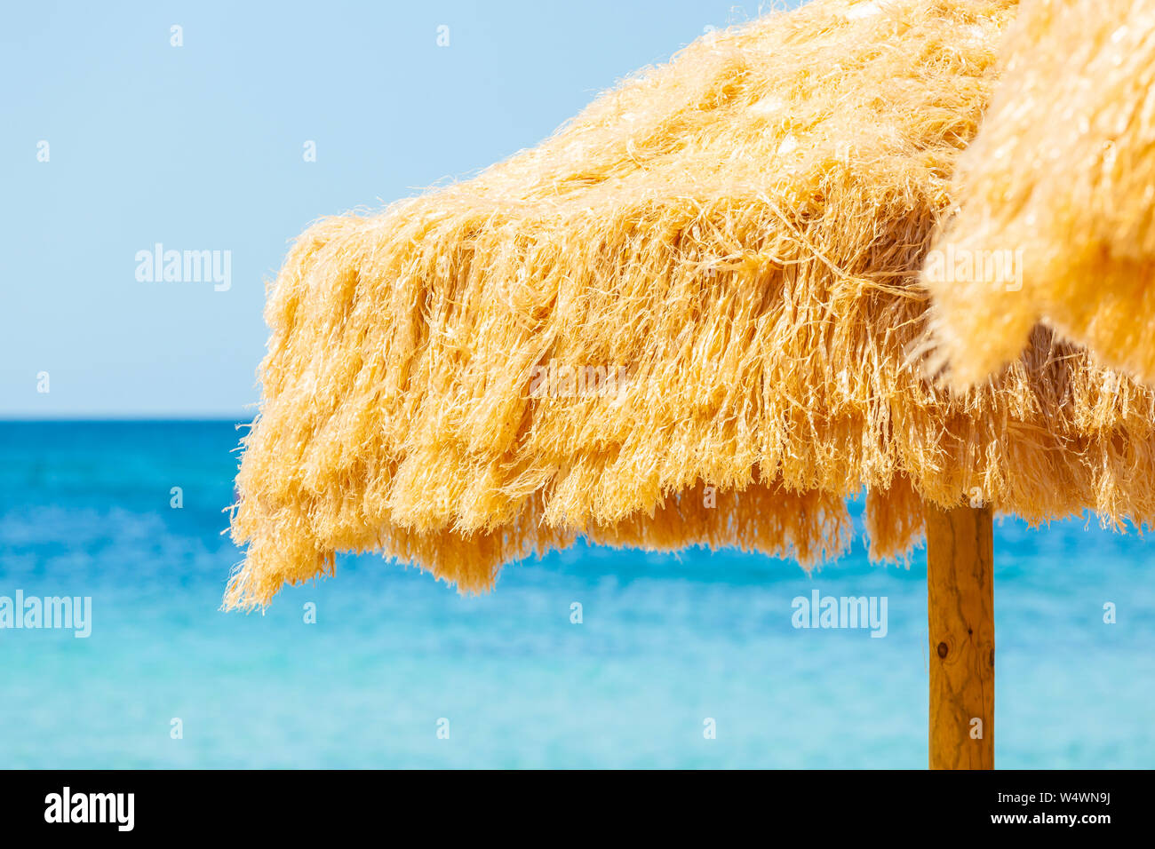 Strand schöne strohgedeckten Sonnenschirmen und leuchtend türkisfarbene Meer, tolle Erholung und Entspannung. Stockfoto