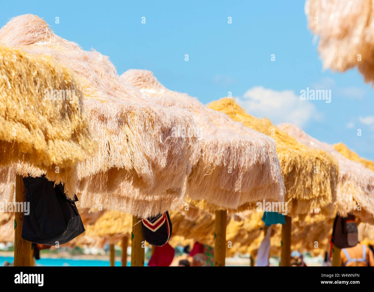 Strand schöne strohgedeckten Sonnenschirmen und leuchtend türkisfarbene Meer, tolle Erholung und Entspannung. Stockfoto