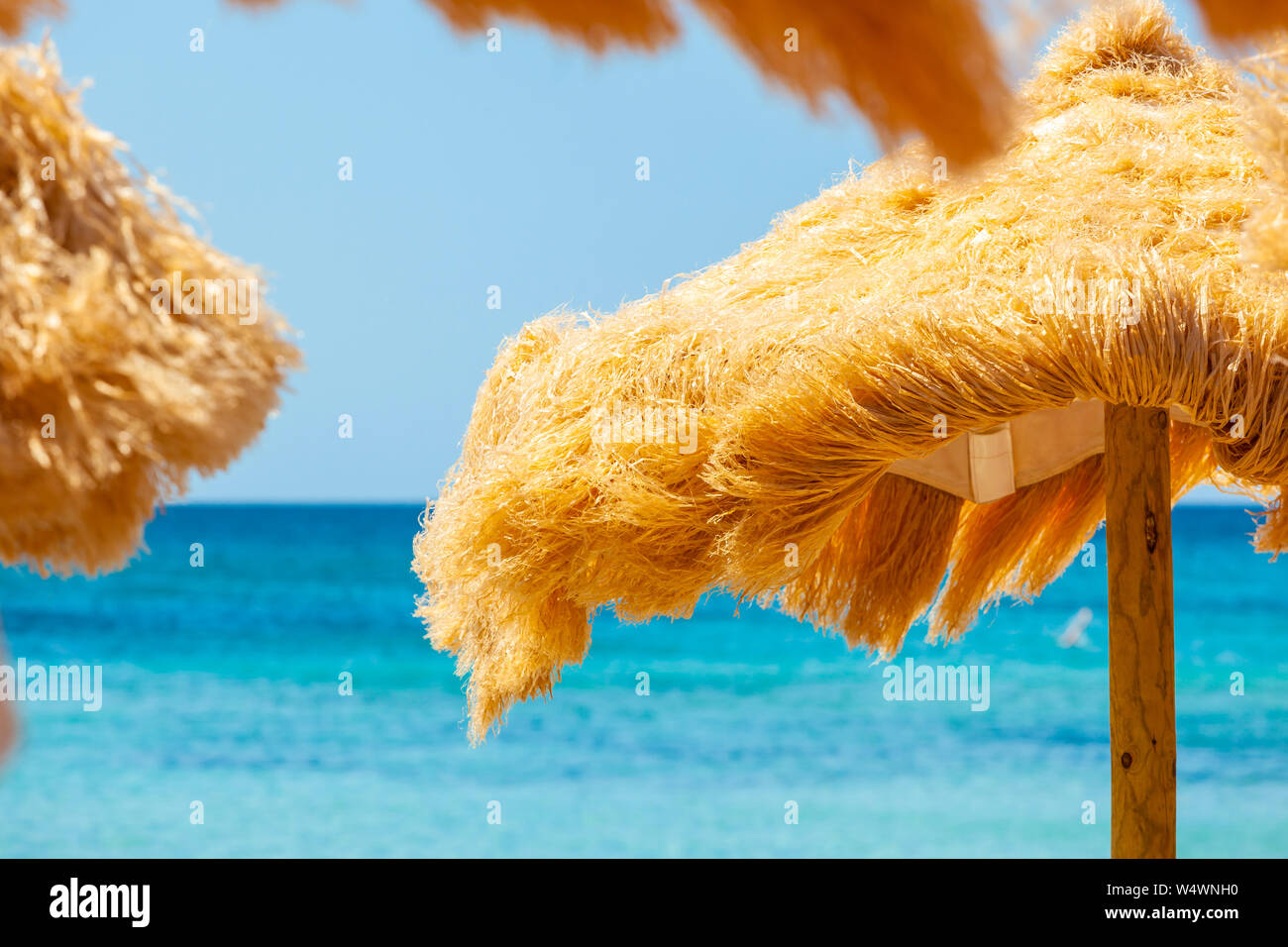 Strand schöne strohgedeckten Sonnenschirmen und leuchtend türkisfarbene Meer, tolle Erholung und Entspannung. Stockfoto