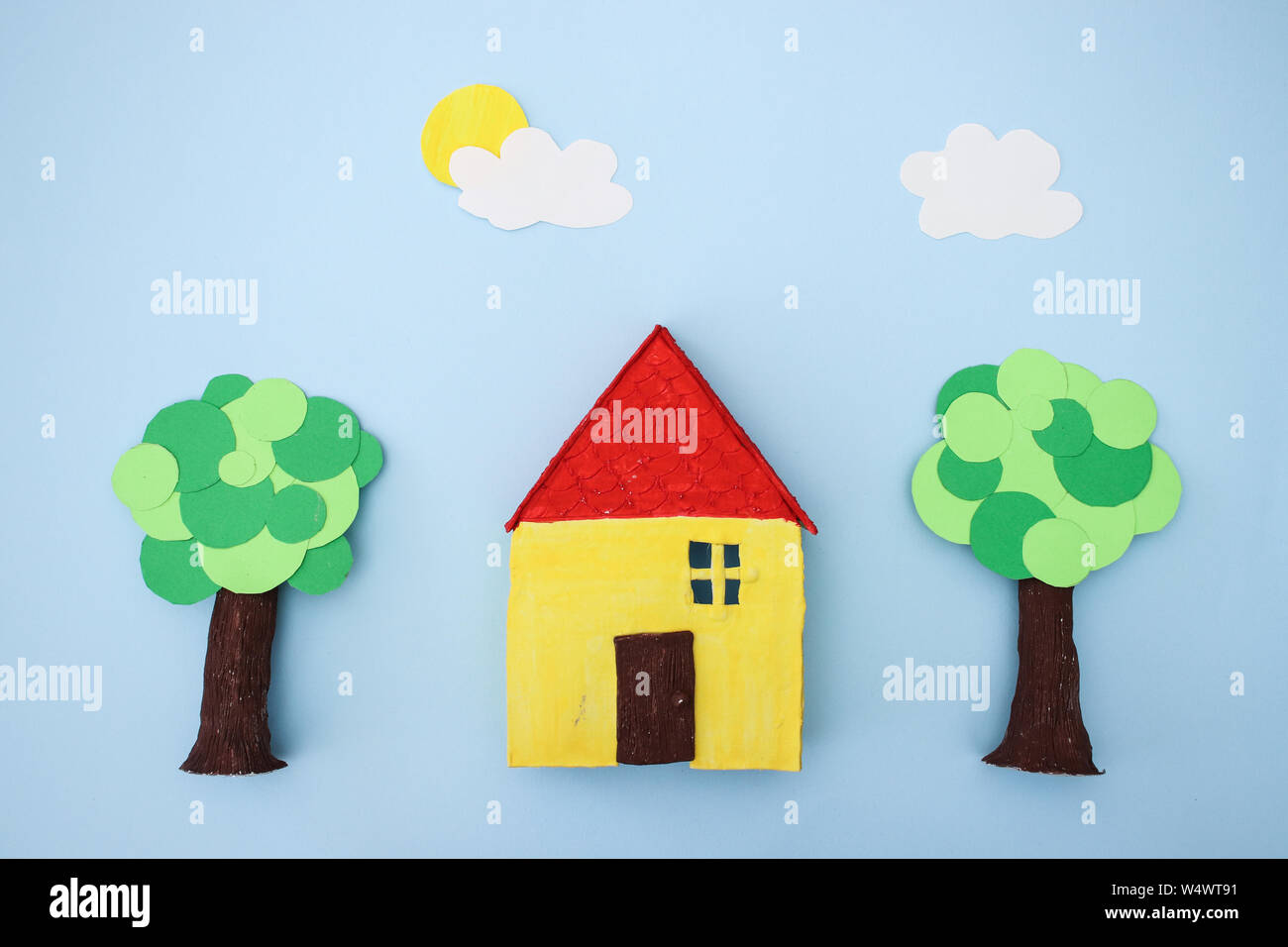 Hand Made gelbes Haus und Bäume auf blauem Hintergrund Stockfoto