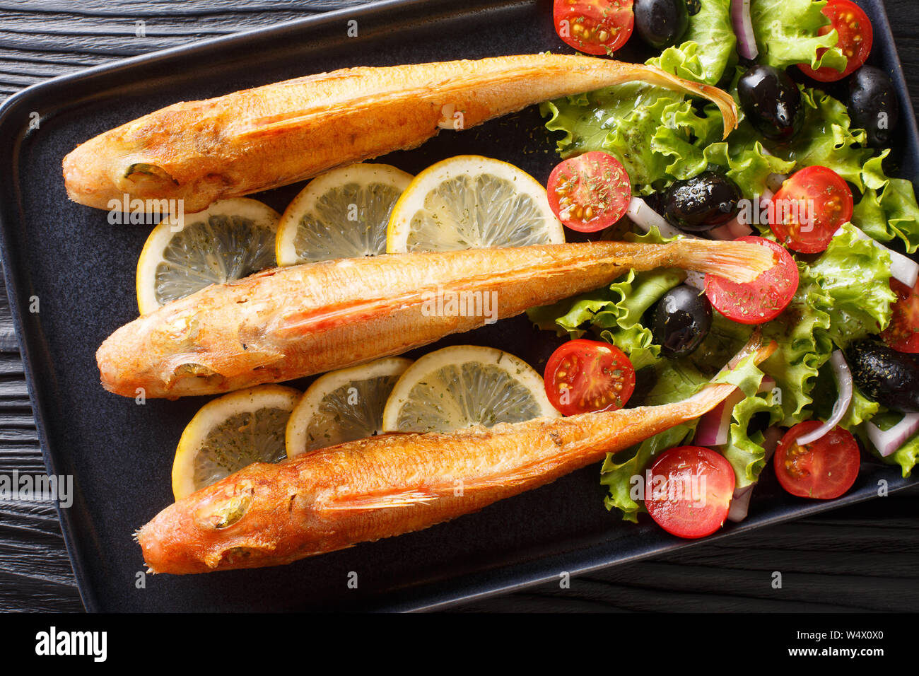 Köstliche frische gebratene Fische Knurrhahn mit frischem Gemüse und Salat Zitrone close-up auf einem Teller auf den Tisch. horizontal oben Ansicht von oben Stockfoto