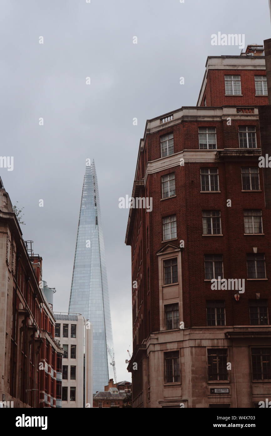 Sie können Sie unter einem alten Suchen rötliche Haus vor dem modernen Shard Wolkenkratzer in London, UK. Alte und neue einen Kontrast im Bild erstellen. Stockfoto