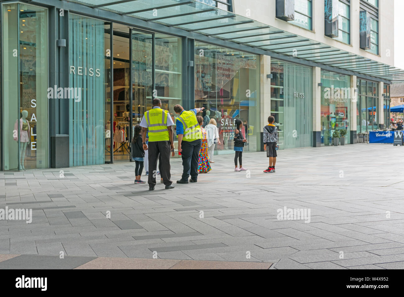 Zwei Sicherheit Personal tragen hohe Sichtbarkeit jacken Leitung einer Gruppe von Menschen außerhalb der Highcross Einkaufszentrum, Leicester, England Großbritannien Stockfoto