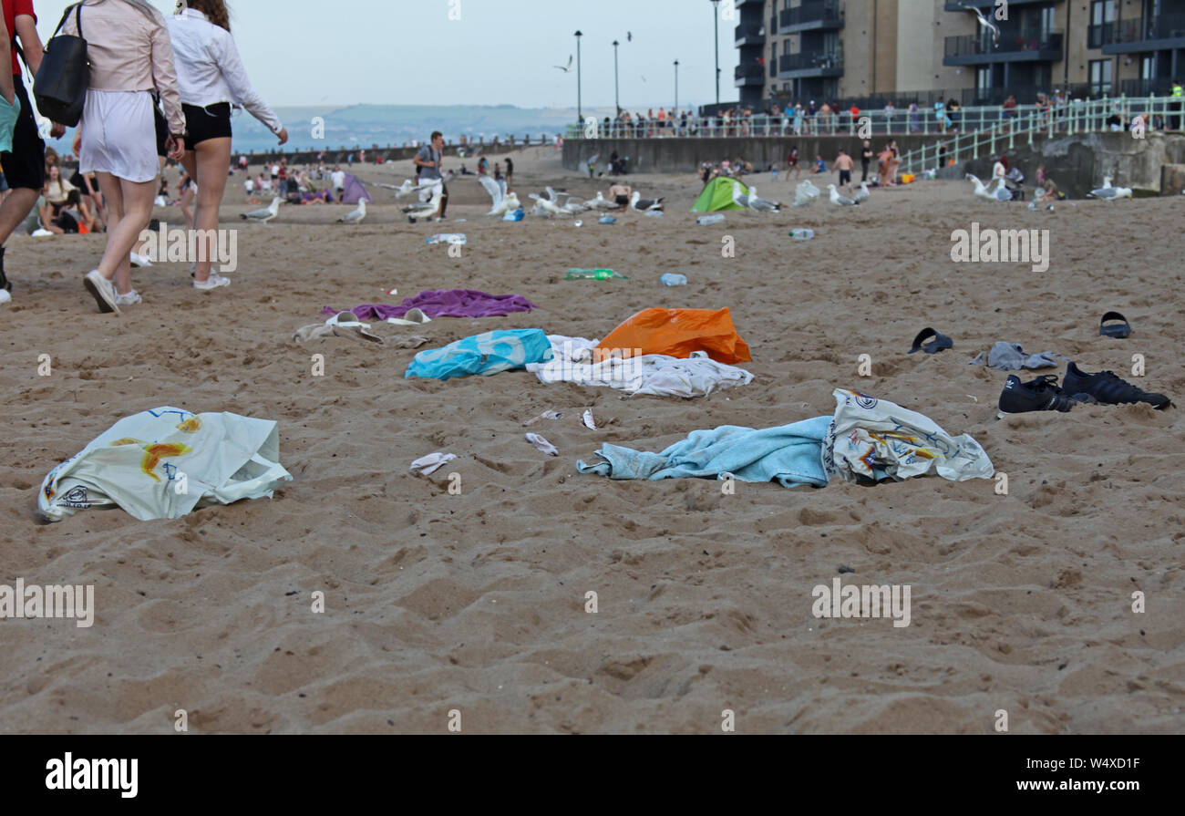 Portobello, Edinburgh, Schottland, Großbritannien. 25. Juli 2019. Gegen 17.30 Uhr am Donnerstag Abend mindestens zehn Polizei Autos, in denen im Beweis neben der Promenade, wie sie genannt worden war hinsichtlich der auftretenden Probleme zwischen Jugendlichen auf Portobello Beach. Um 18.30 Uhr hatten die meisten Jugendlichen verstreut in Richtung der Bus hält an der Portobello Road. Läßt eine Verwirrung auf dem Sand weggeworfene Kleidung und Müll. Stockfoto