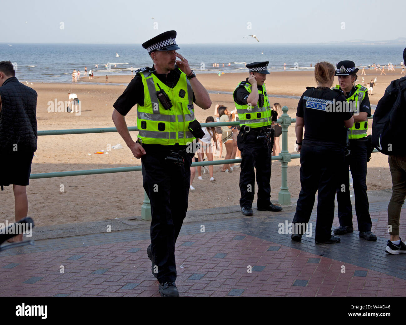 Portobello, Edinburgh, Schottland, Großbritannien. Juli 2019. Gegen 17.30 Uhr waren am Donnerstagabend mindestens zehn Polizeiwagen unterwegs, die neben der Promenade, wie sie wegen Unruhe zwischen Jugendlichen am Portobello Beach gerufen worden waren, unterwegs waren. Bis 18.30 Uhr waren die meisten Jugendlichen verstreut. Auf dem Sand von ausrangierter Kleidung und Müll verwirren. Stockfoto