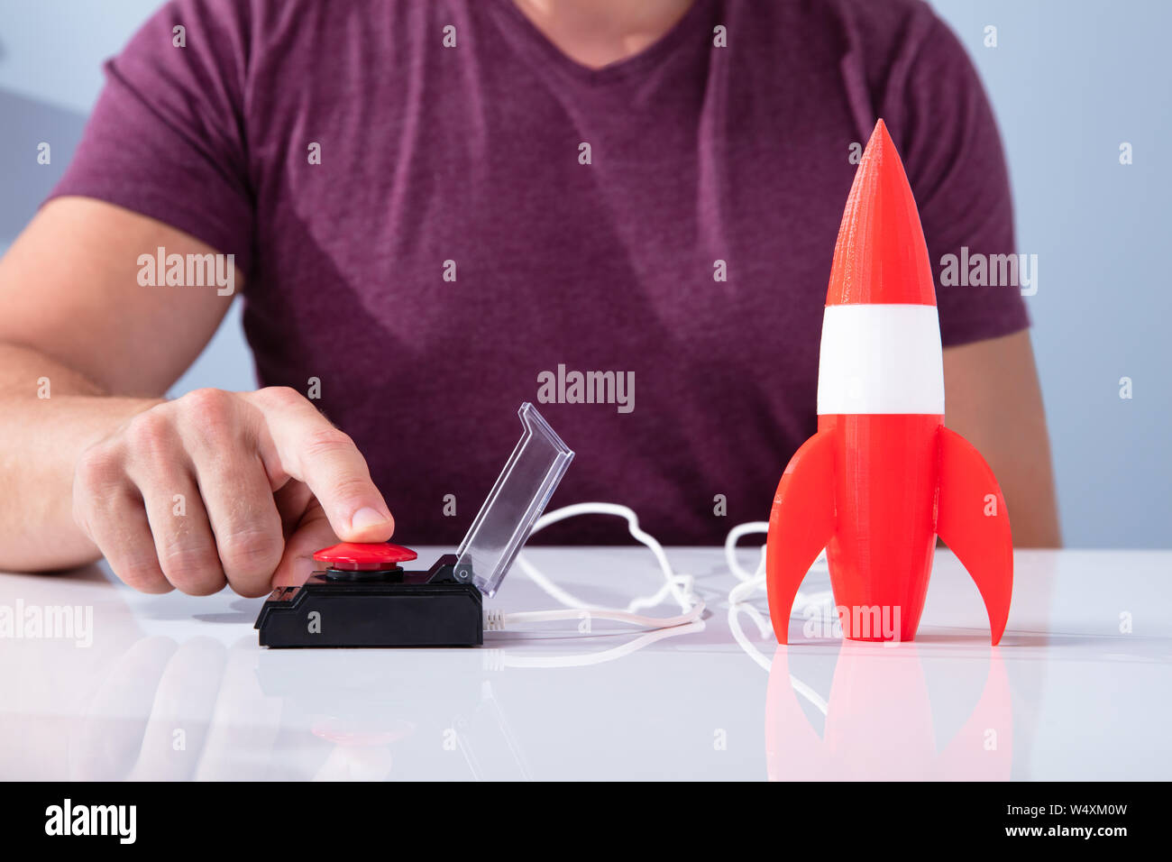 Des Menschen Hand mit Raketen durch Drücken der roten Taste Über reflektierende Schreibtisch Stockfoto