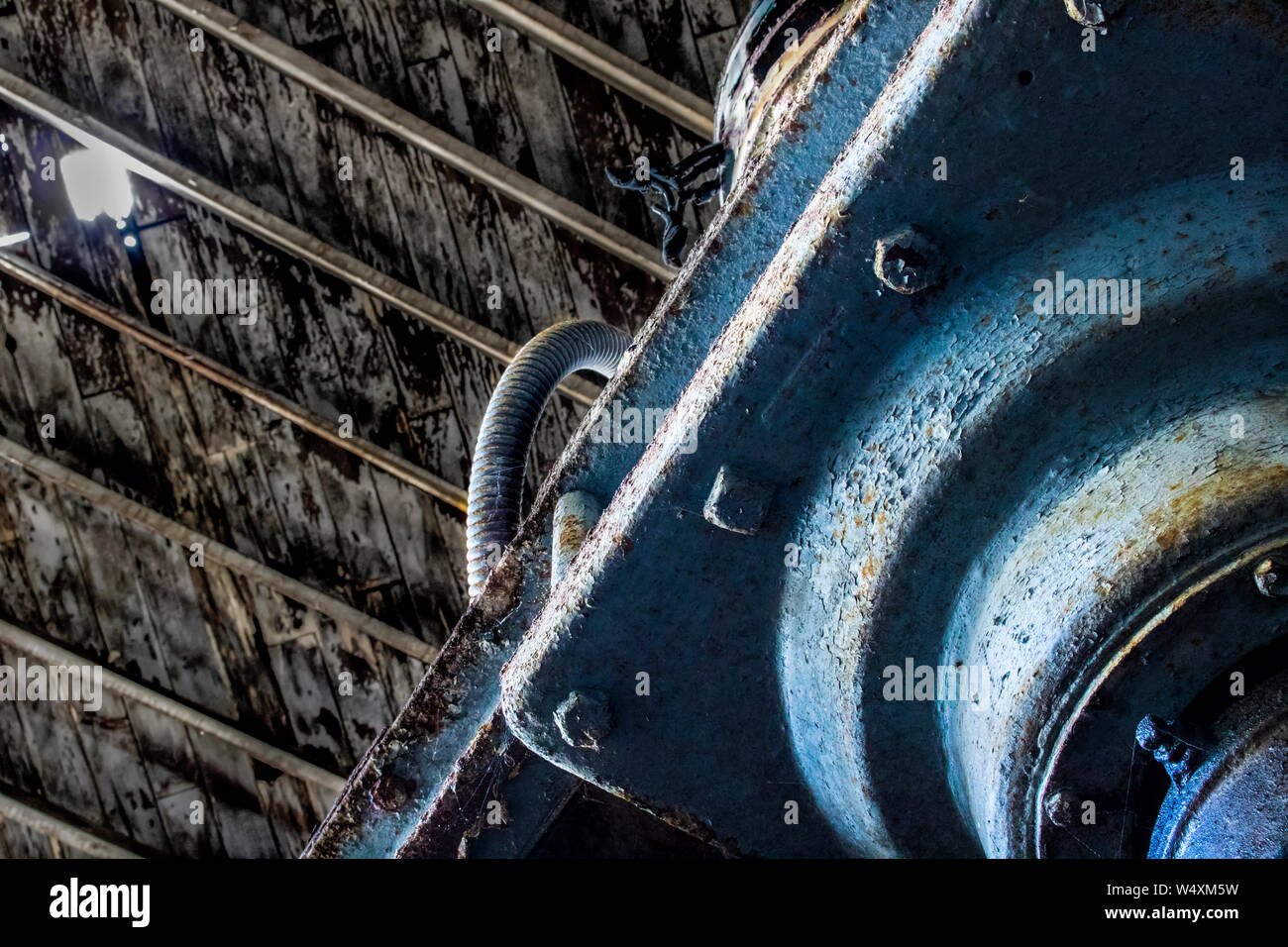 Blau die Farbe kam von rostigem Eisen Maschinen unter holz Decke öffnen zum Himmel durch fehlende Schindeln. Bild in verlassenen Lager entnommen. Stockfoto