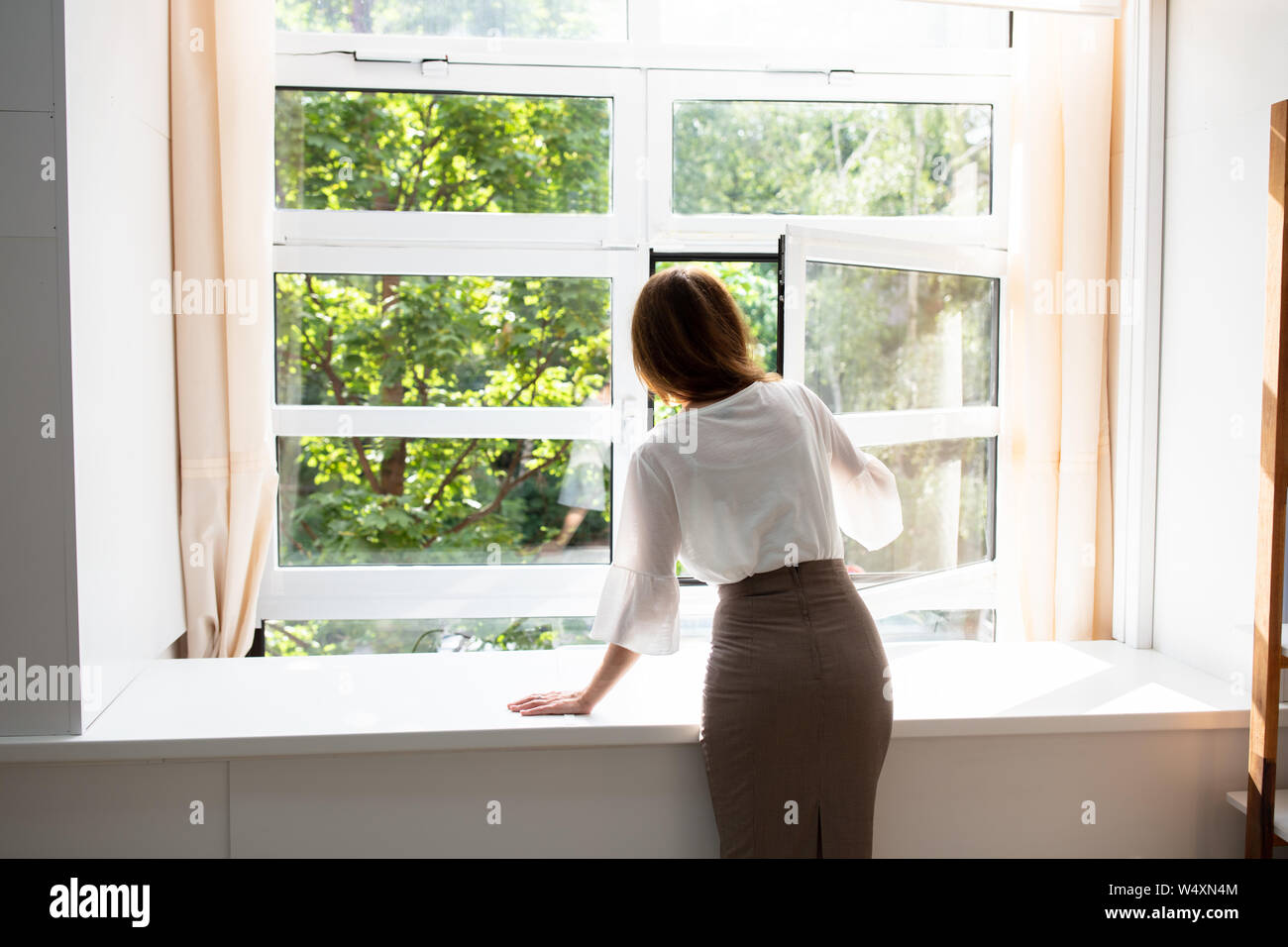 Seitenansicht einer Geschäftsfrau, die durch ein Fenster von einem Bürogebäude Stockfoto