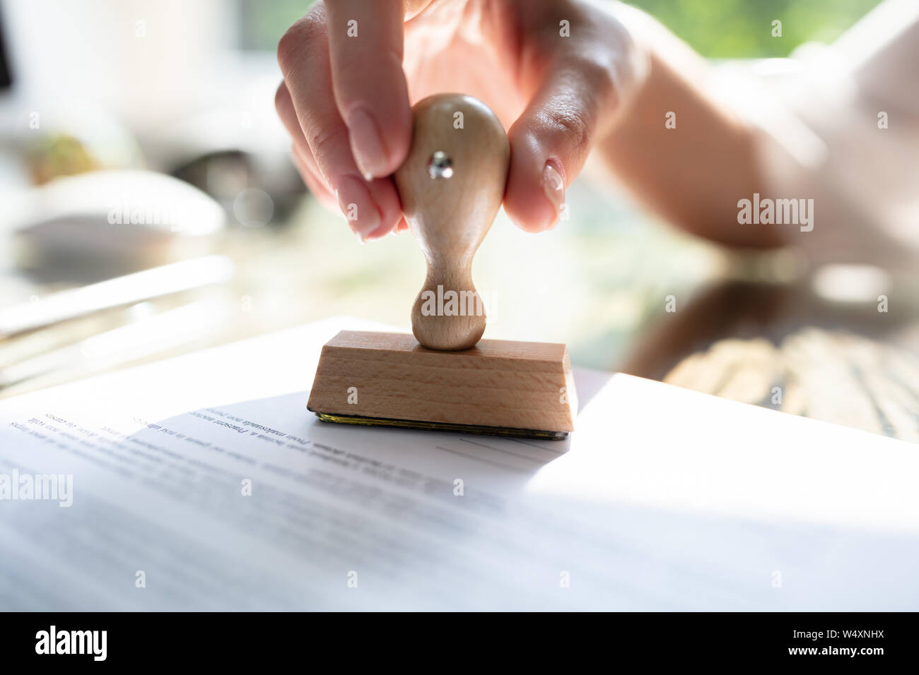 Nahaufnahme der Geschäftsfrau Hand Stanzen Genehmigt auf Vertrag Papier mit Stamper Stockfoto