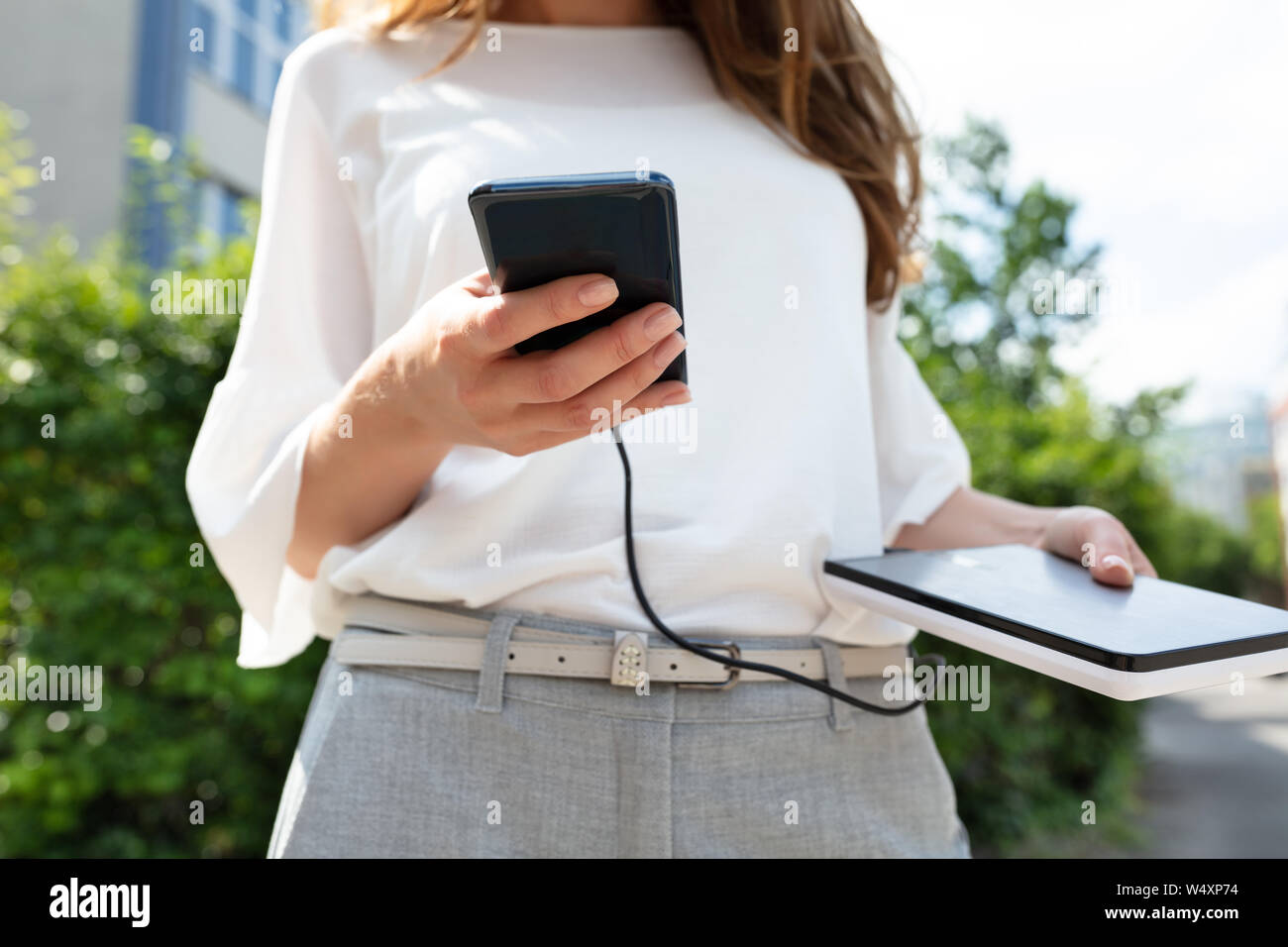 Nahaufnahme von Frau mit Mobiltelefon und externe Batterie Stockfoto