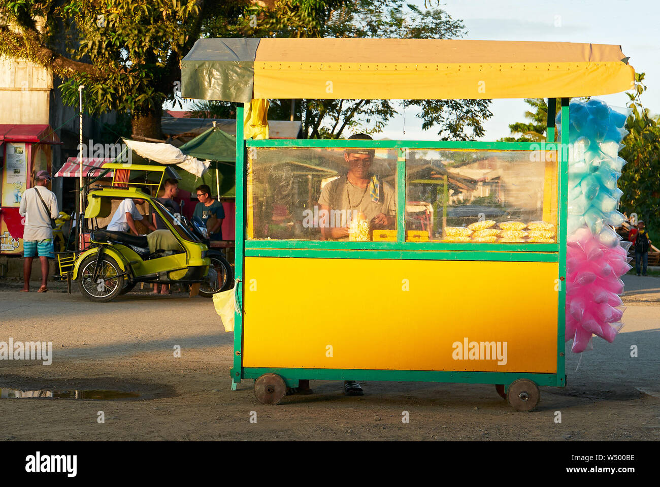 Cuartero, Capiz Provinz, Philippinen: Junger Mann Verkauf von Popcorn und Zuckerwatte in einem kleinen gelben Schubkarre am späten Nachmittag Stockfoto